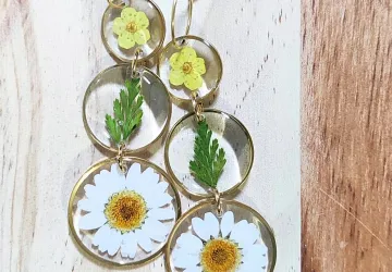 Pendientes largos de triple circules tipo bisel de acero inoxidable dorado con tres tipo de flores y hojas en su interior. Gancho tipo aro.