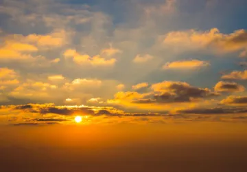 Sol brillando en el horizonte con nubes
